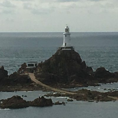 Phare de La Corbière sur la côte de Jersey avec vue sur la mer et les rochers.